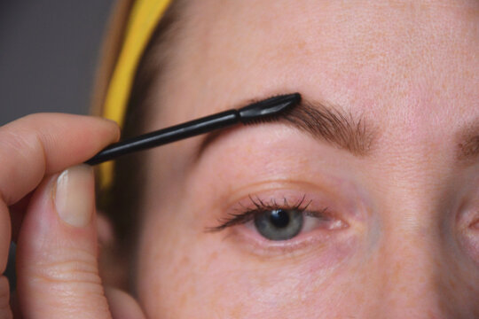 Close up of combing eyebrow with spoolie brush
