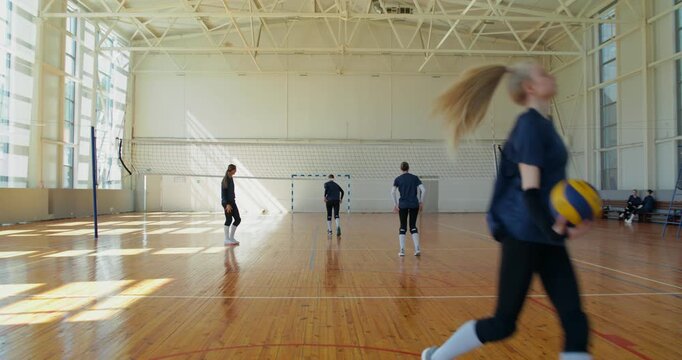 The girls lose the balls during practice and quickly pick them up.. Female volleyball players meet before training, then practice receiving and passing the ball in pairs.
