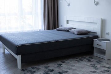 Bedroom with big bed near window. Minimalism bedroom interior.