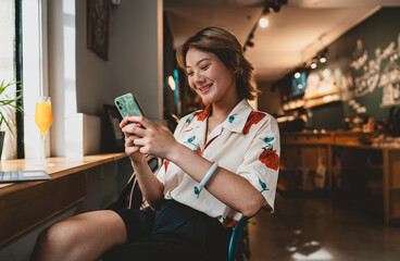 Close-up of cheerful Asian woman holding phone and stylus, expressing happiness, connection, and...