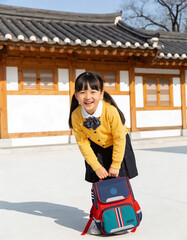 Happy asian little schoolgirl with backpack in Korean traditional house.