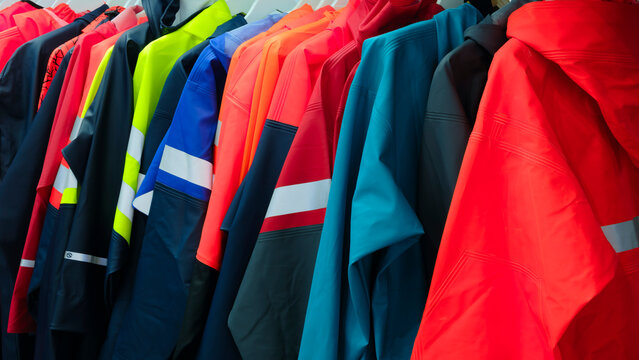 Multi-colored industrial protective clothing for work in extreme, harmful, aggressive conditions hangs on hangers on a stand.
