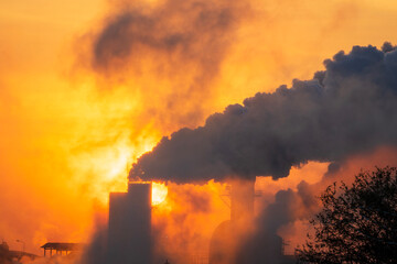 Black smoke moving up polluting atmosphere during sunrise. Smoke from industrial chimneys, environmental problems, air pollution.