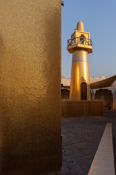 Doha, Qatar - 06 November 2025: View of the golden minaret and building reflecting the warm light against the cool blue sky.