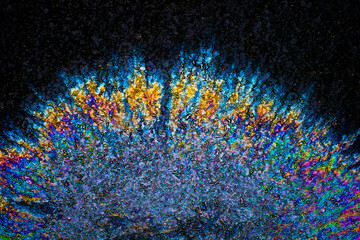 a photograph of an oil or petrol stain on a wet asphalt or pavement surface, a phenomenon called iridescence. interference of light waves reflecting off the different layers of the thin oil film