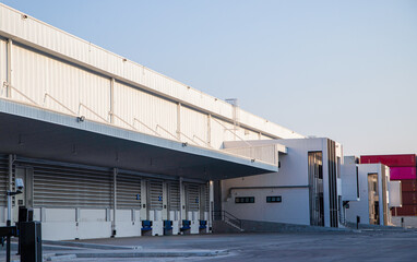 Warehouse exterior with loading ramps and slots for trucks to park - modern industry warehouse storage building.