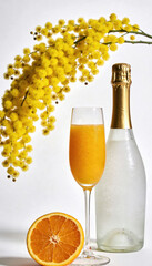 Glass of mimosa cocktail with chilled champagne bottle and fresh orange