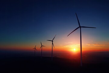 Obraz premium Silhouetted wind turbines against a vibrant sunset sky, representing renewable energy sources