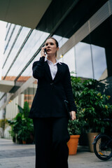 Fototapeta premium Low angle shot of businesswoman talking on smartphone, highlighting leadership, mobile control and digital authority in modern professional communication.