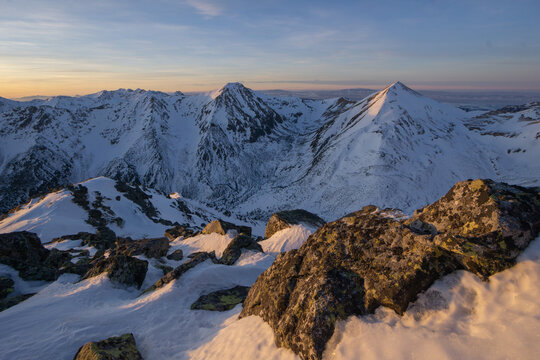 View of snow-blanketed peaks kissed by the rising sun, rugged rocks dusted with frost in the foreground, Nizna Bystra, Zilina Region, Slovakia.