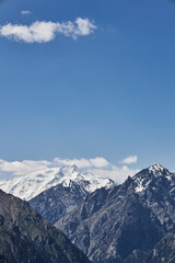 Obraz premium Majestic snow-capped mountain peaks under a clear blue sky, illustrating natural grandeur and serene wilderness. Scenic landscape for travel and adventure.