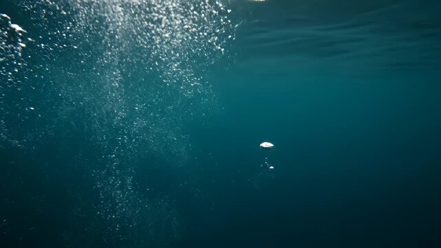 Underwater bubbles rising in deep blue water