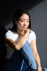 グレー背景で自然光を浴びる日本人女性