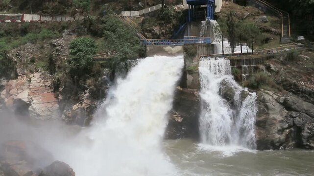 Maneri Dam, a concrete gravity dam on the Bhagirathi River near Uttarkashi, releases powerful water flow through rocky terrain, highlighting hydropower and Himalayan landscape.