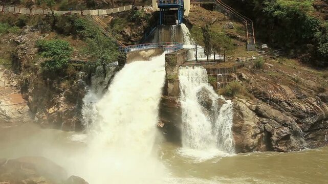 Maneri Dam, a concrete gravity dam on the Bhagirathi River near Uttarkashi, releases powerful water flow through rocky terrain, highlighting hydropower and Himalayan landscape.