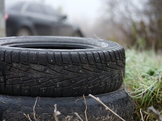 A close-up of two studded winter tire in stack outdoors.