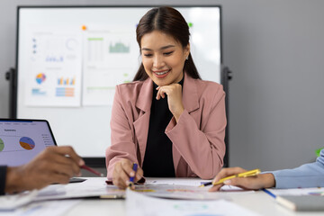 Marketing team analyzing financial reports discussing company marketing strategy pointing at charts and graphs displayed on table during meeting in office boardroom.