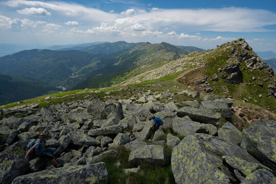 View of rocky terrain under a vast sky where distant mountain peaks fade into the horizon, offering a challenging yet scenic hike, Nizke Tatry, Slovakia.