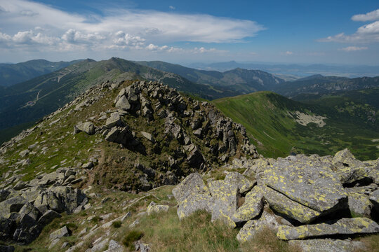 View of rugged, rocky terrain gives way to verdant slopes under a bright sky, Dumbier, Nizke Tatry, Zilinsky region, Slovakia.
