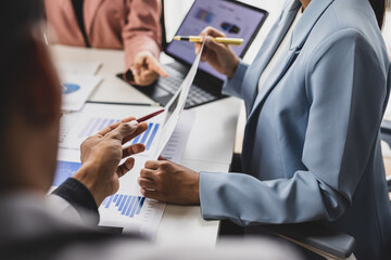 Business colleagues are collaborating on a project, analyzing financial data and company performance using various charts, graphs, and reports during a meeting.