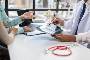 Doctor explaining diagnosis to a concerned couple in a hospital office.
