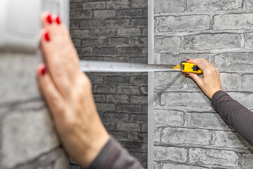 A woman measures a doorway with a tape measure. a measuring tape in a woman's hands. woman doing home renovations. 