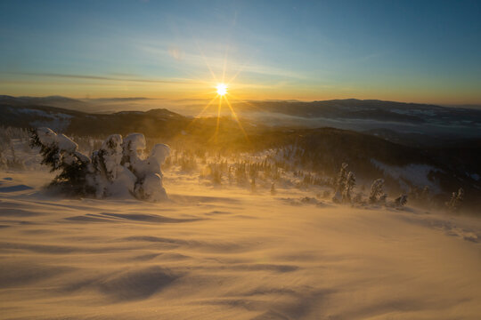 View of golden sunlight kisses the snow-laden landscape, the wind sculpting frozen waves across the ground in Nizke Tatry, Nizke Tatry, Slovakia.