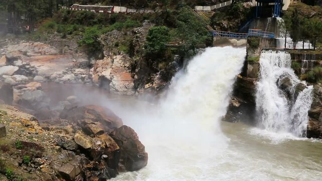 Maneri Dam, a concrete gravity dam on the Bhagirathi River near Uttarkashi, releases powerful water flow through rocky terrain, highlighting hydropower and Himalayan landscape.