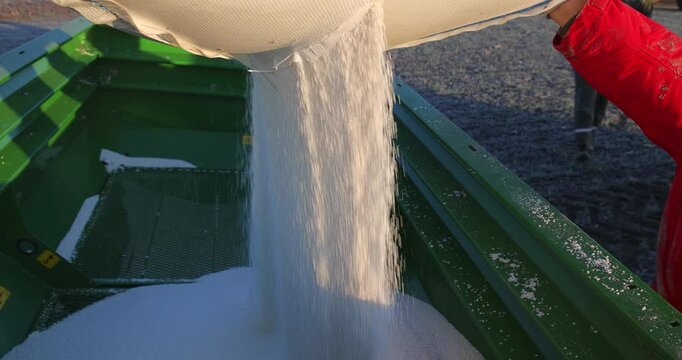 Pouring mineral fertilizer in granules into the fertilizer spreader. Proper growth and development of plants requires a balance of nutrients found in the soil