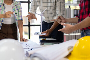 Engineers discussing about wind turbine and building model during meeting.