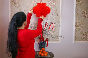 Girl decorating room for Chinese New Year with red lanterns and oranges