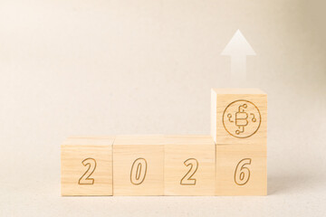 Wooden blocks showing year 2026 with a Bitcoin icon and upward arrow, representing cryptocurrency market growth, financial trends, investment success, and digital asset bullish forecast in 2026.