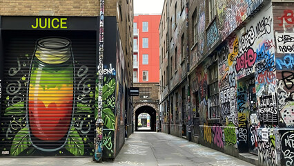Vibrant street art featuring juice mural in narrow alleyway