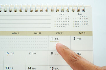 Finger pointing at calendar highlighting Labour Day, symbolizing workers appreciation, public holiday, employment rights, social contribution, annual observance, and work life balance awareness.