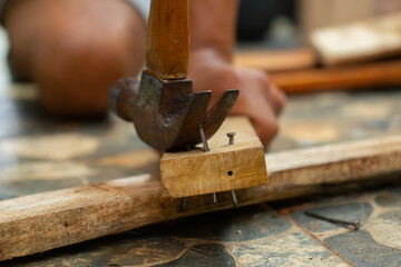 a worker removing nail on wood beam using with a claw hammer, in a workshop environment