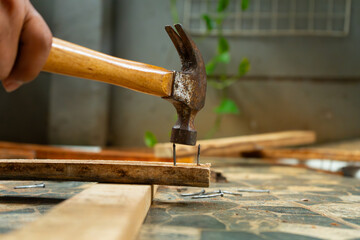 a worker removing nail on wood beam using with a claw hammer, in a workshop environment