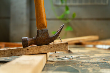 a worker removing nail on wood beam using with a claw hammer, in a workshop environment