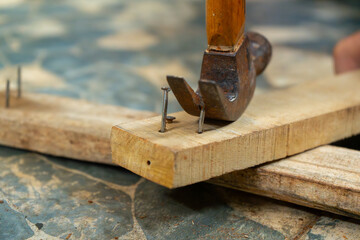a worker removing nail on wood beam using with a claw hammer, in a workshop environment