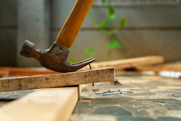 a worker removing nail on wood beam using with a claw hammer, in a workshop environment