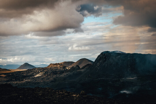 View of stark, black volcanic rock formations stretch under a sky of brooding clouds and soft, diffused light, a scene of raw natural power, Fagradalsfjall, Reykjanes Peninsula, Iceland.