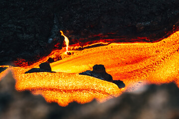 View of fiery molten lava flows like a river of destruction, contrasting against the dark, rugged earth, a dance of heat and stone, Fagradalsfjall, Reykjanes Peninsula, Iceland.
