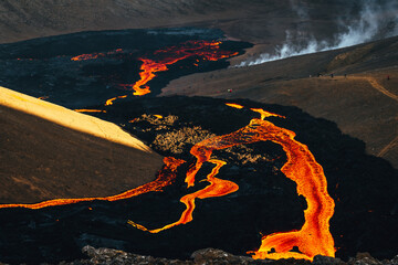 View of fiery rivers of molten lava snake through dark volcanic landscape, contrasting with the distant figures observing the spectacle, Fagradalsfjall, Reykjanes Peninsula, Iceland.