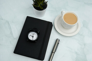 Minimal flat lay business workspace with notebook, watch, pen, coffee, and plant on marble...