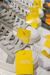 Paris, France - 01 10 2026: Gray and white sports shoes putting on shelves with sale tags in a...