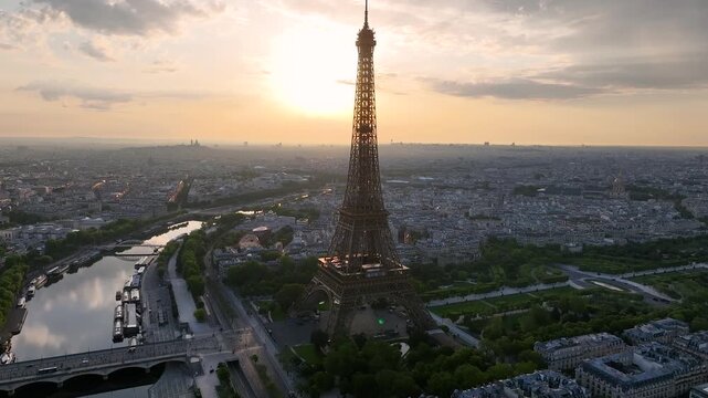 Aerial drone view of the streets of Paris, France, overlooking the famous Eiffel Tower and Champ de Mars at sunrise or sunset. Sun rays pass through the tower. Cinematic 4k. Europe from above