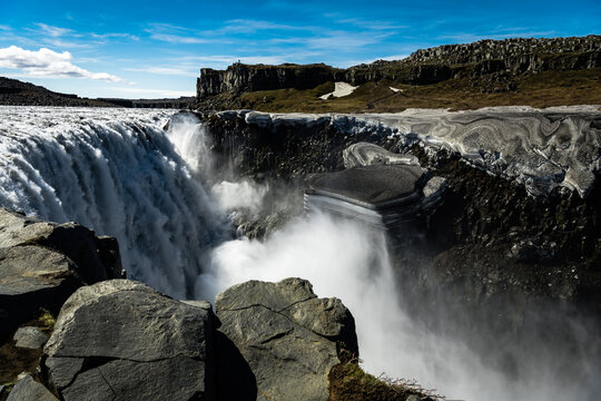 View of Dettifoss waterfall's powerful cascade plunges into a misty abyss, framed by rugged cliffs and a clear blue sky in Vatnajokull Park, Northeast Iceland, Iceland.