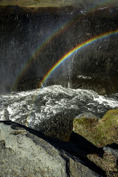 View of a vibrant rainbow arcing across the misty spray rising from the powerful Dettifoss waterfall, a spectacle of nature's force and beauty, Vatnajokull Park, Northeast Iceland, Iceland.