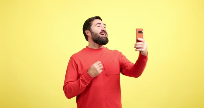 Happy bearded man waving during a video call on yellow background