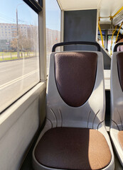 Empty bus seat with brown upholstery and sunlight streaming through the window, creating a warm atmosphere, inviting public transport experience