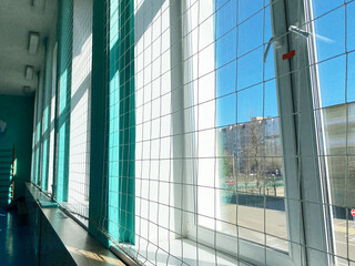 Interior of a school gym with large windows, bright natural light illuminating the space, showcasing a vibrant environment for sport education and physical activities